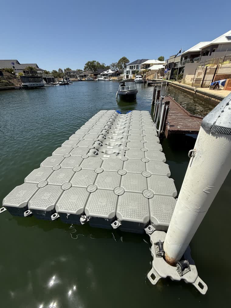 A black boat approaching a floating dock