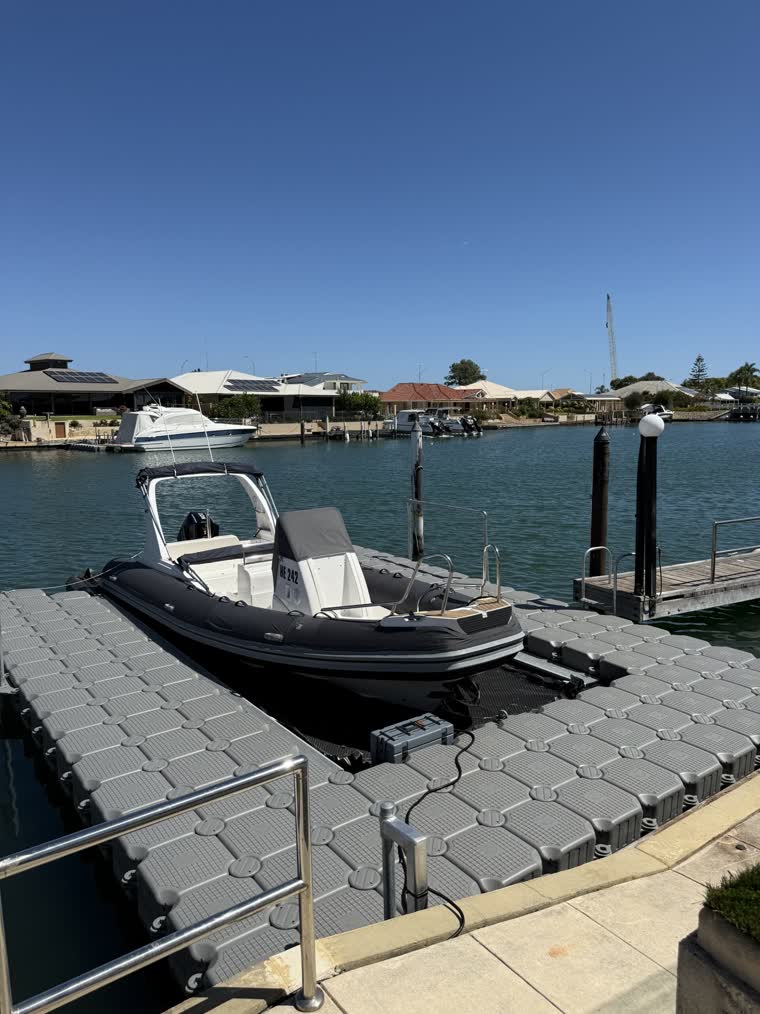 A boat docked under the sun with a pier leading onto the dock