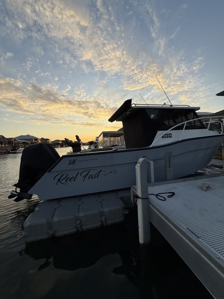 Side view of a boat on a partly cloudy day as the sun sets