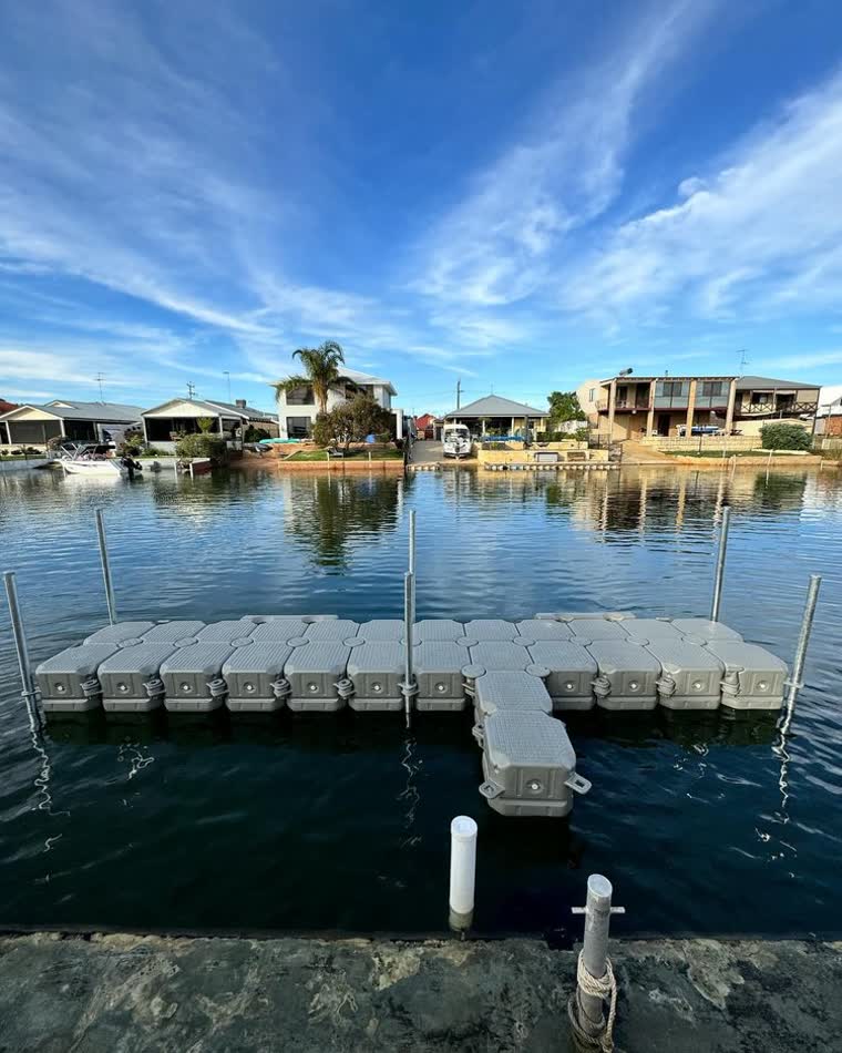 Floating Dock with 6 metal poles supporting it on a body of water
