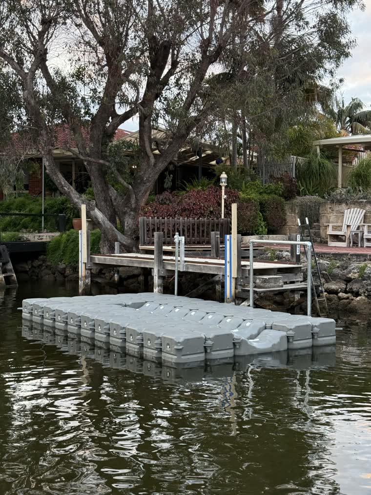 Floating empty dock in front of a house that has a big tree