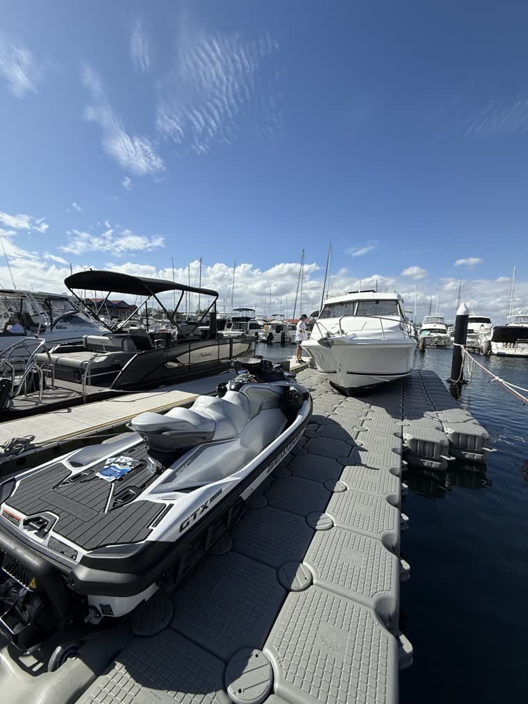 Closeup image of a jetski and a boat on the same dock, multiple boats visible on the background