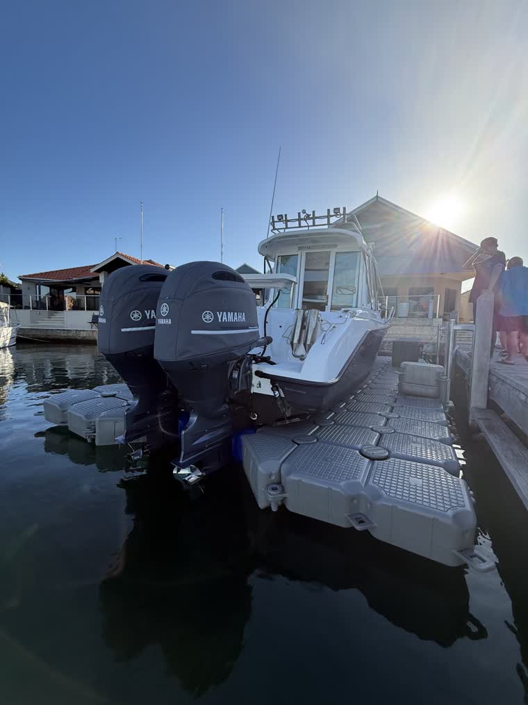 Photo of a boat from behind, showing engines and people standing by the dock