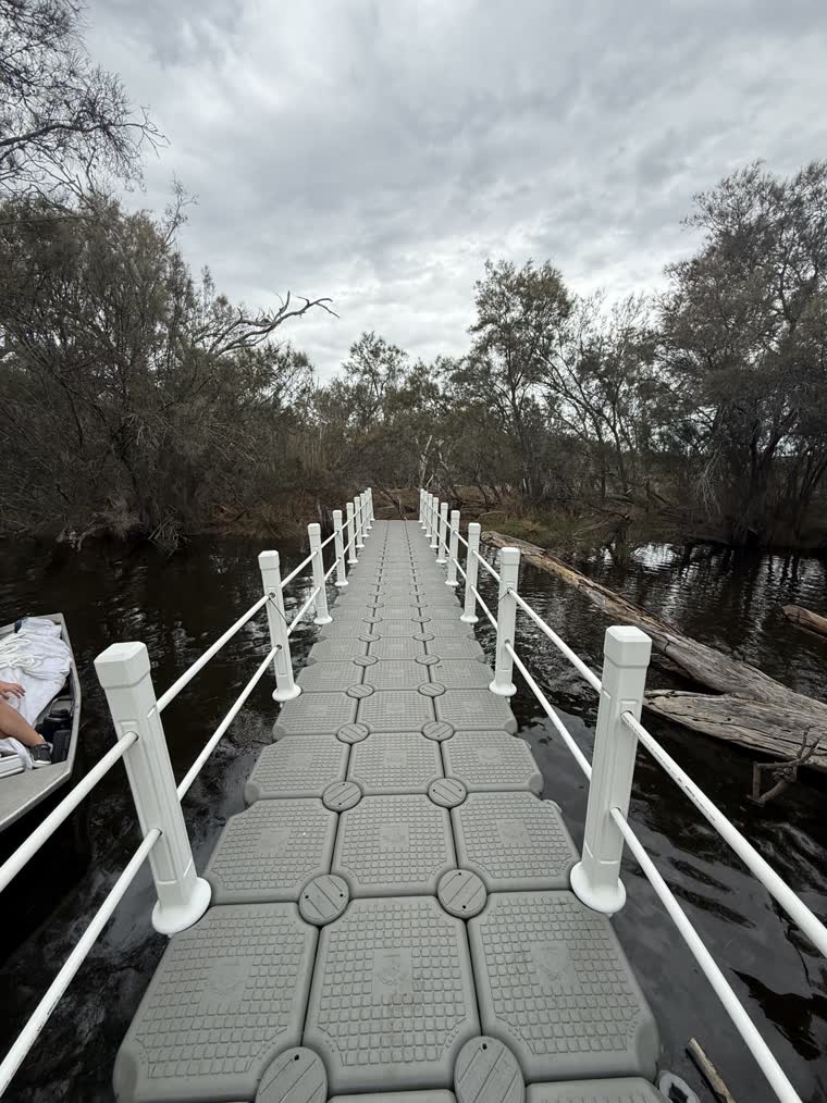 Image of a walkway dock leading to land, a boat visible on the left side