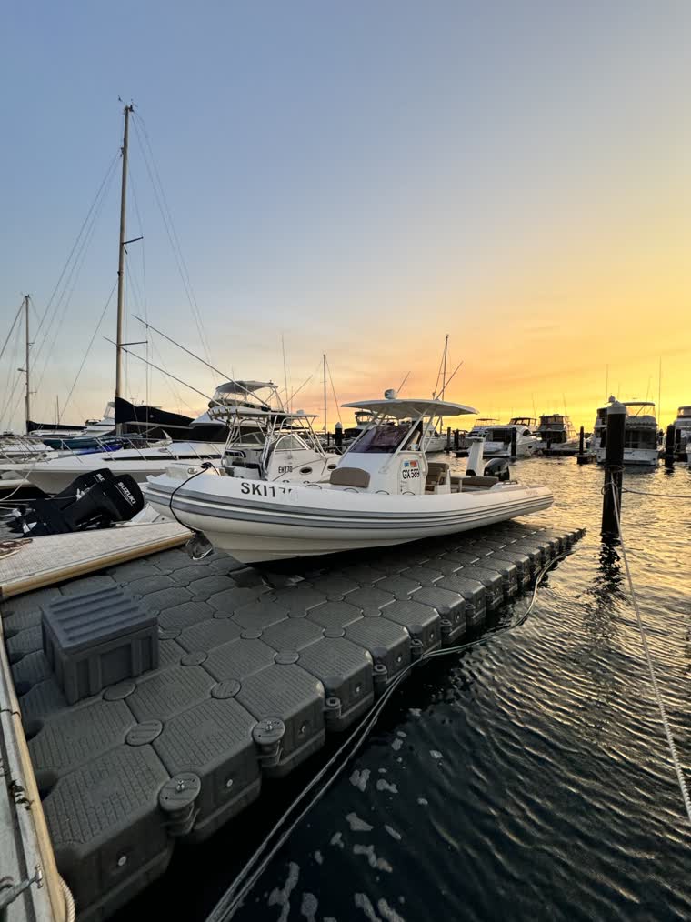 A white boat parked on a dock during the yellow to orange sunset