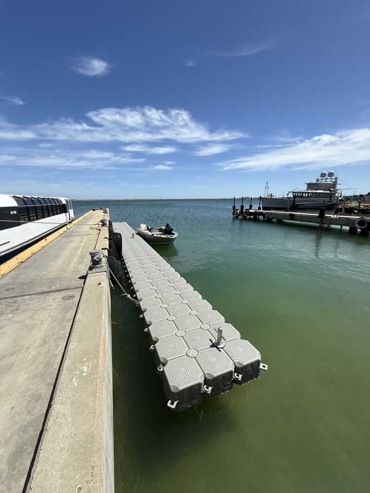 Work and walkway platform on a sunny day with a small boat by the side of the dock